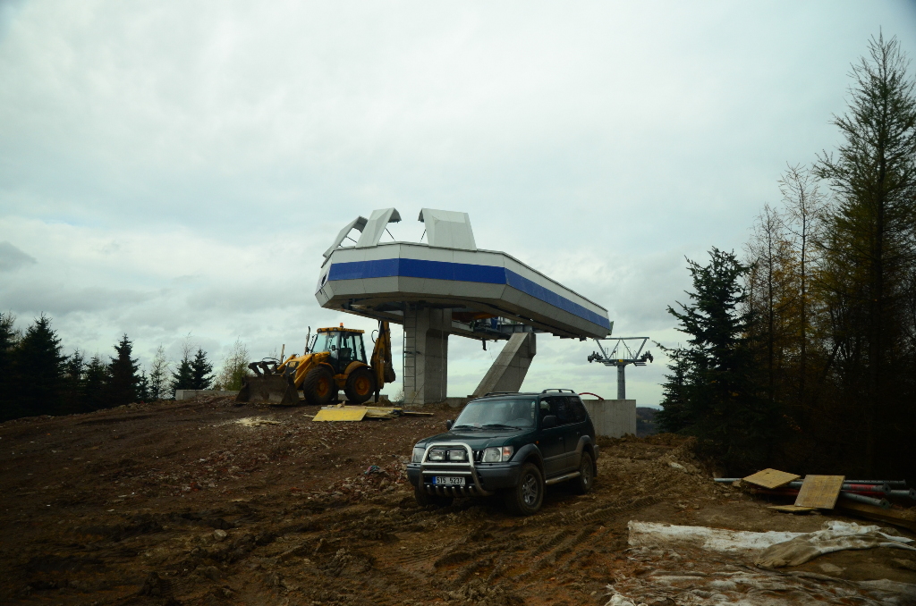 Bergstation für Seilbahn, ein Bager und ein Auto steht davor, grauer Himmel